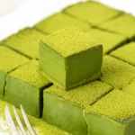 A bowl of smooth, vibrant green matcha chocolate mixture being poured into a square dish.