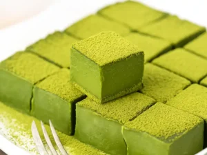 A bowl of smooth, vibrant green matcha chocolate mixture being poured into a square dish.