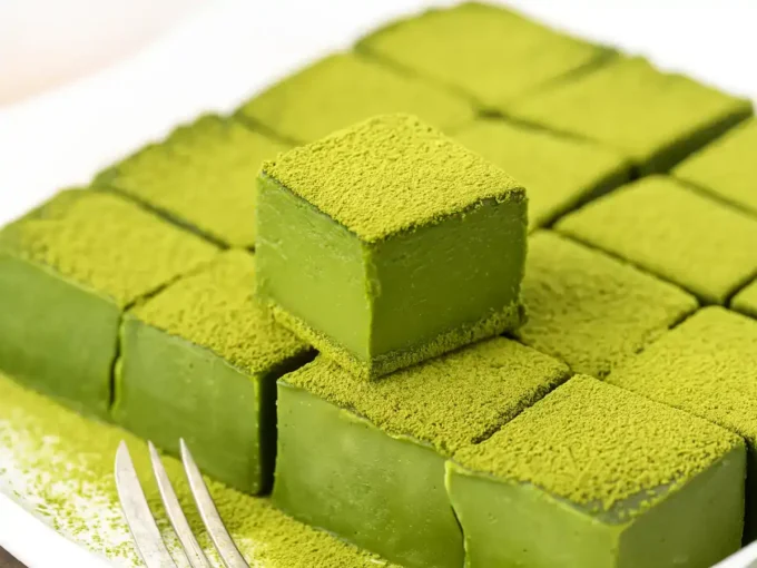 A bowl of smooth, vibrant green matcha chocolate mixture being poured into a square dish.