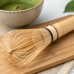 Matcha whisk resting on a kusenaoshi stand, showing fine bamboo prongs and craftsmanship.