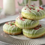 A stack of glazed Matcha Donuts on a plate, topped with sprinkles, showcasing the green tea flavor.